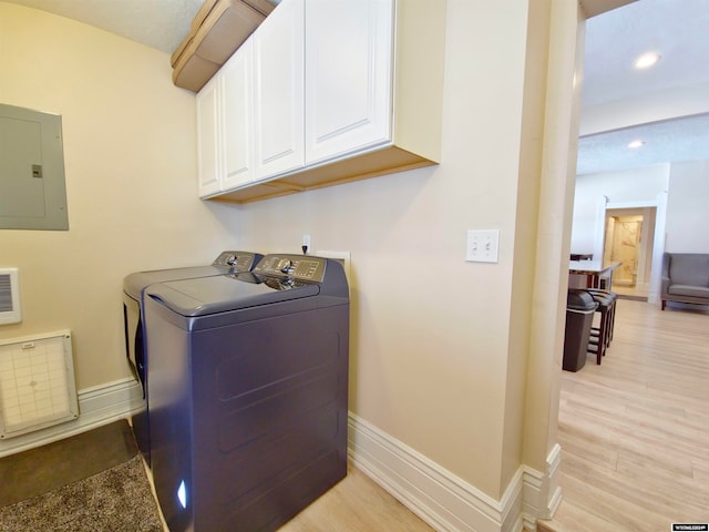 laundry room with washing machine and dryer, cabinets, electric panel, and light wood-type flooring