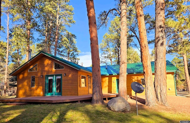 back of property with a lawn, french doors, and a deck