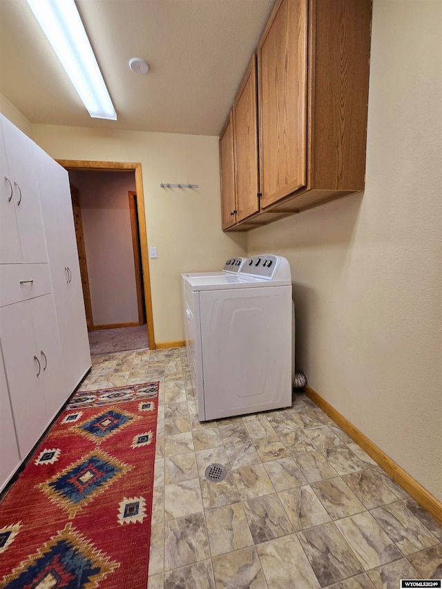 clothes washing area featuring washer and clothes dryer and cabinets