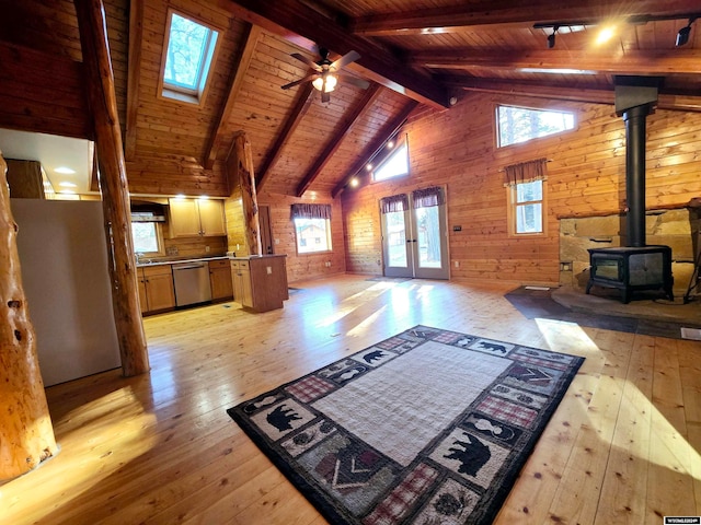 living room featuring beam ceiling, a wood stove, light hardwood / wood-style floors, wooden walls, and wood ceiling