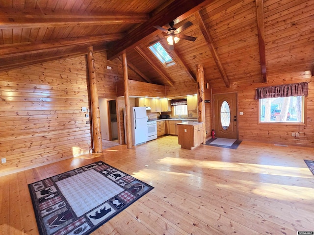 unfurnished living room featuring ceiling fan, wood walls, lofted ceiling with skylight, light hardwood / wood-style floors, and wood ceiling