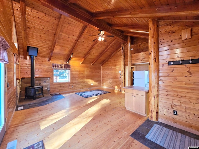 unfurnished living room with a wood stove, vaulted ceiling with beams, wood walls, light hardwood / wood-style floors, and wood ceiling