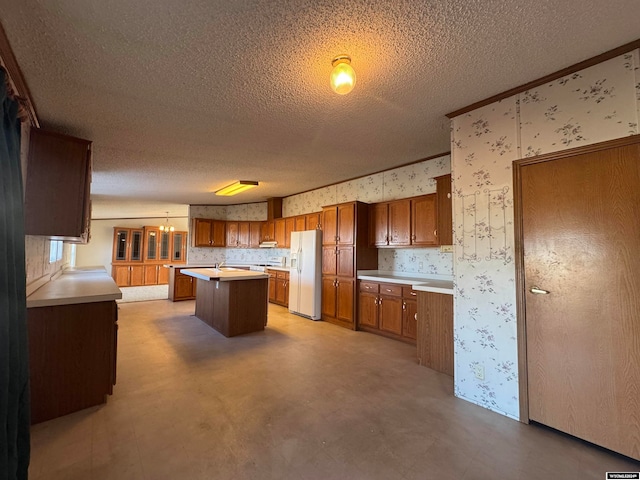 kitchen featuring decorative light fixtures, a center island, white refrigerator with ice dispenser, and a textured ceiling