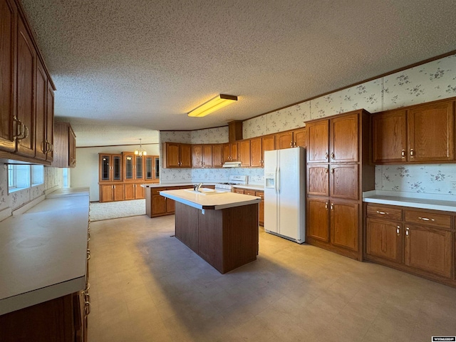 kitchen featuring a textured ceiling, white appliances, exhaust hood, a kitchen island, and hanging light fixtures