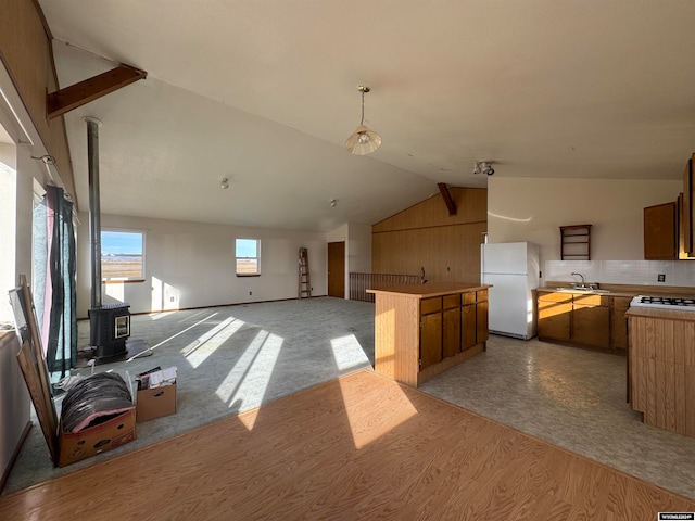 kitchen featuring vaulted ceiling, sink, white refrigerator, light hardwood / wood-style floors, and a wood stove