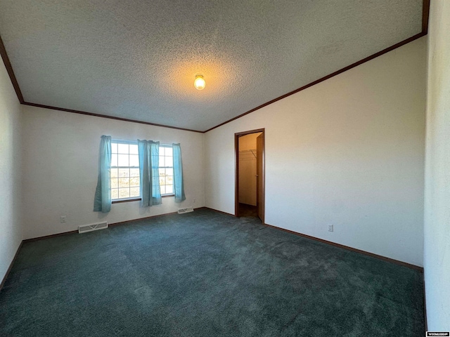 carpeted spare room with vaulted ceiling, crown molding, and a textured ceiling