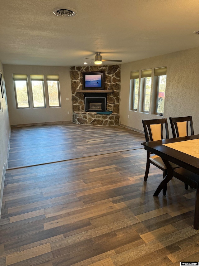 living room featuring plenty of natural light, a fireplace, dark wood-type flooring, and ceiling fan