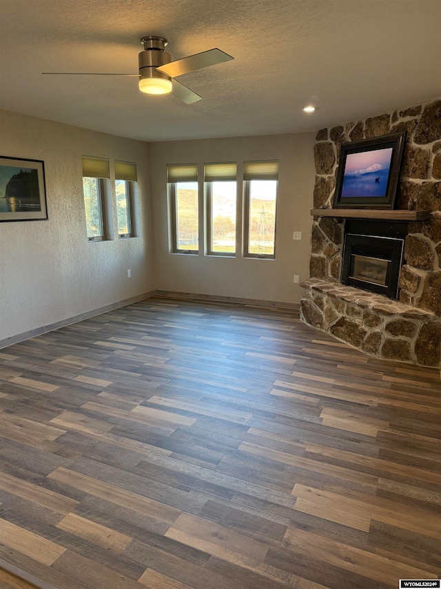 unfurnished living room with dark hardwood / wood-style floors, a healthy amount of sunlight, a fireplace, and ceiling fan