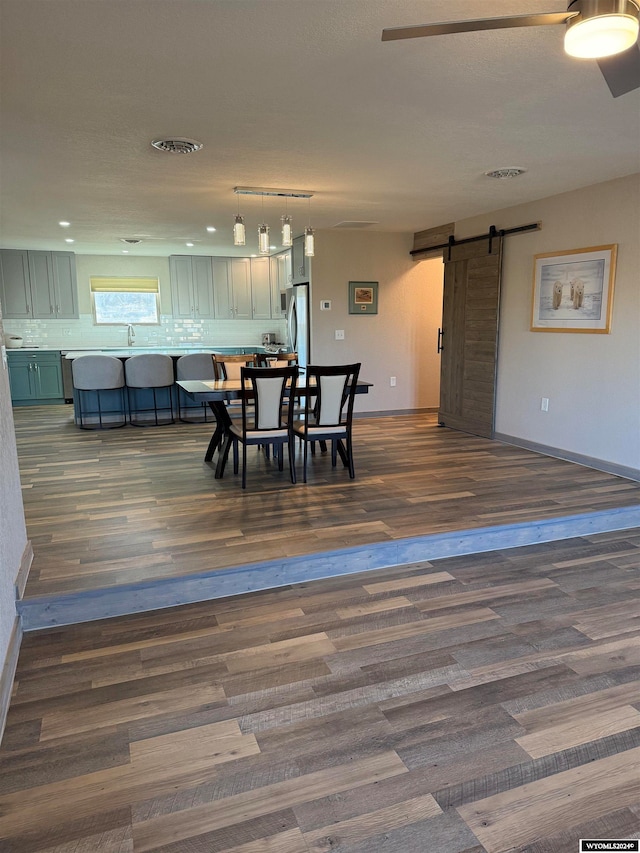 dining area with a barn door and dark wood-type flooring