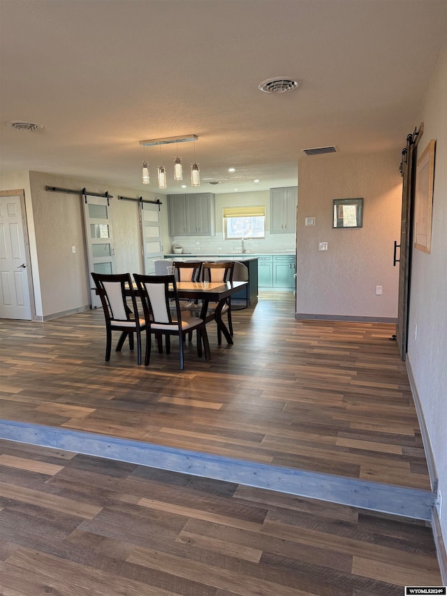 dining room featuring a barn door, dark hardwood / wood-style floors, and sink