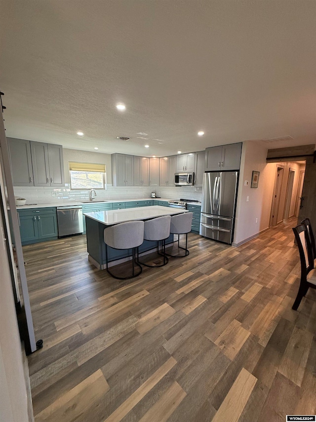 kitchen with a breakfast bar, stainless steel appliances, sink, dark hardwood / wood-style floors, and a kitchen island