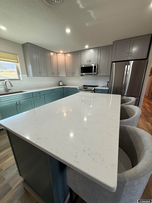 kitchen featuring light stone countertops, stainless steel appliances, dark wood-type flooring, and sink