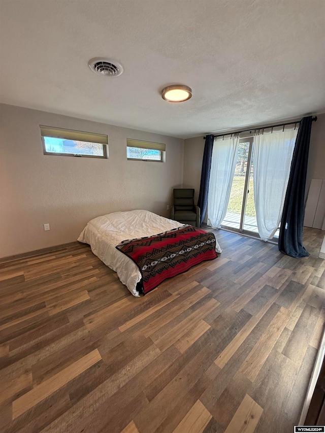 bedroom featuring a textured ceiling, access to exterior, dark wood-type flooring, and multiple windows