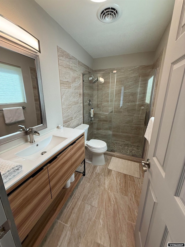 bathroom featuring vanity, toilet, and a shower with shower door