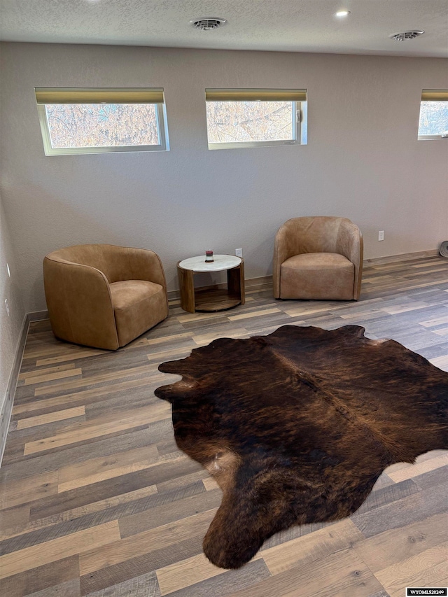 living area featuring hardwood / wood-style flooring, plenty of natural light, and a textured ceiling