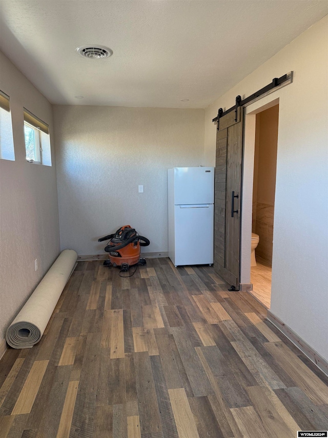 interior space with a barn door and dark hardwood / wood-style floors