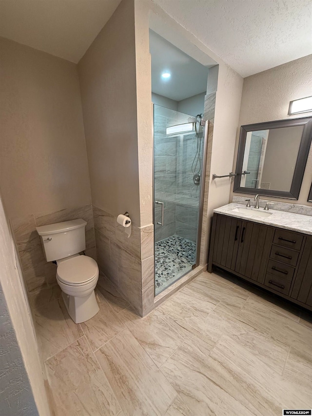 bathroom featuring vanity, toilet, a shower with shower door, and a textured ceiling