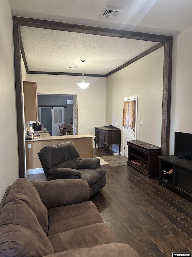 living area featuring crown molding, dark wood finished floors, visible vents, and a textured ceiling