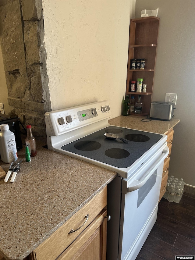 kitchen with light stone counters, white electric range, a textured wall, and dark wood finished floors