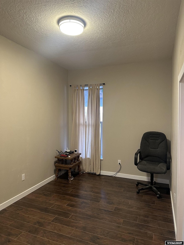 unfurnished office with dark wood-style flooring, baseboards, and a textured ceiling