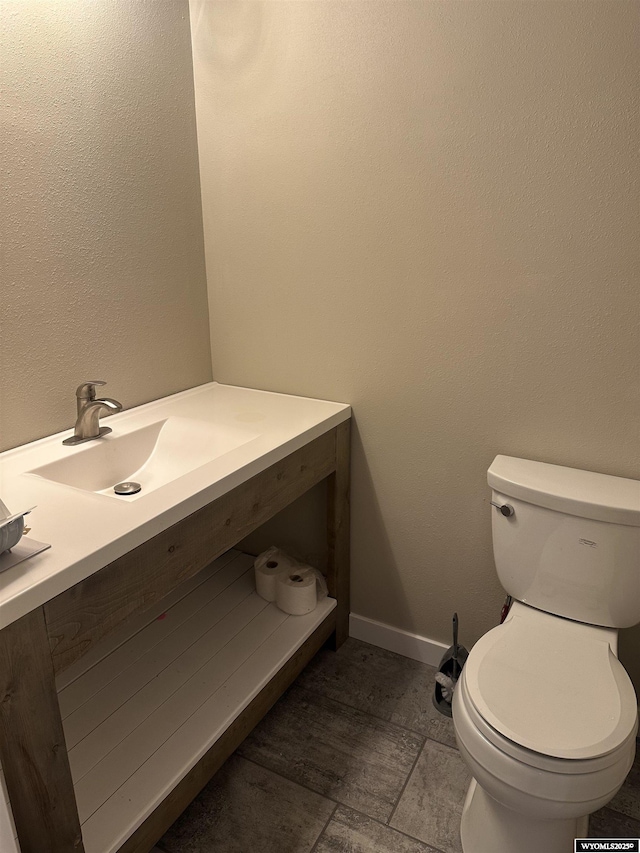 bathroom featuring vanity, baseboards, and toilet