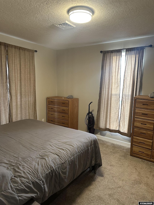 bedroom featuring a textured ceiling, visible vents, and carpet floors