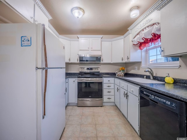 kitchen featuring light tile patterned floors, a sink, appliances with stainless steel finishes, white cabinetry, and dark countertops