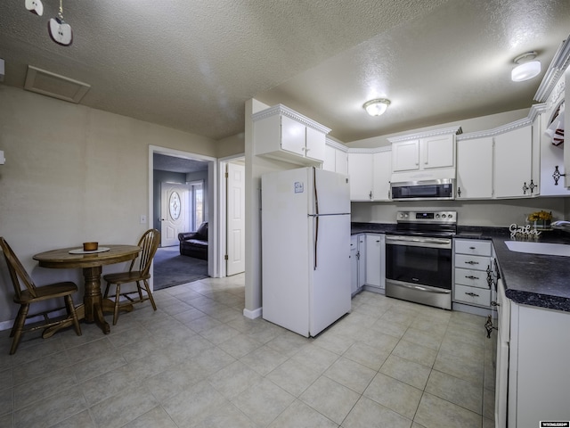 909 Skyline Dr, Douglas, WY 82633 - kitchen with appliances with stainless steel finishes, dark countertops, a sink, a textured ceiling, and white cabinetry