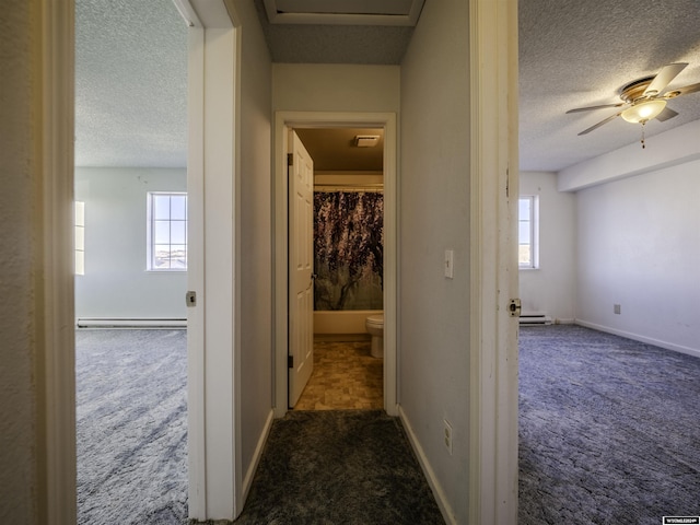 909 Skyline Dr, Douglas, WY 82633 - corridor featuring dark colored carpet, a textured ceiling, a baseboard heating unit, and baseboards