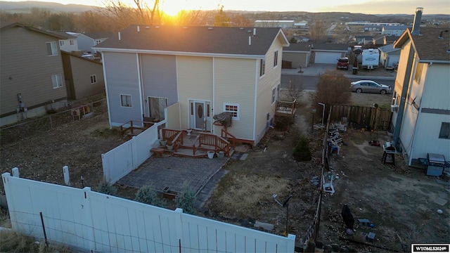 back of house at dusk with a fenced backyard