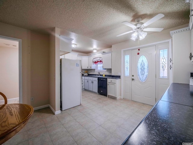 kitchen featuring dark countertops, black dishwasher, freestanding refrigerator, white cabinetry, and a sink