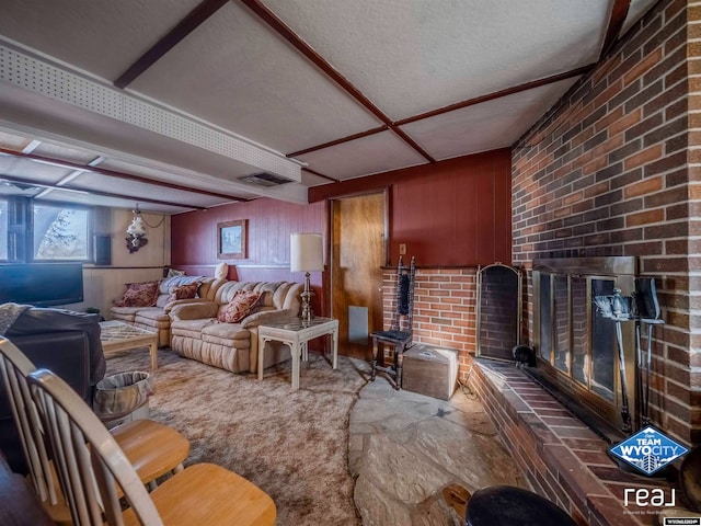 living room featuring wood walls, carpet floors, a textured ceiling, and a brick fireplace