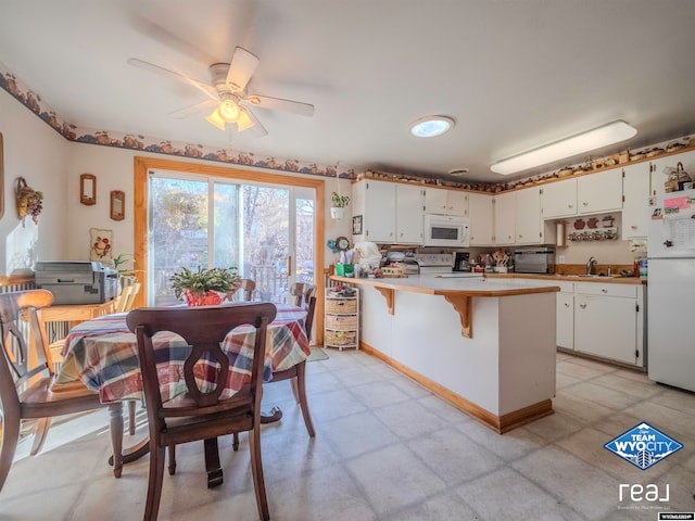 kitchen with white appliances, white cabinetry, ceiling fan, and sink