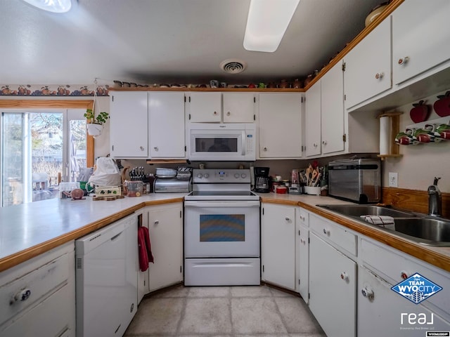 kitchen with white appliances, white cabinetry, and sink