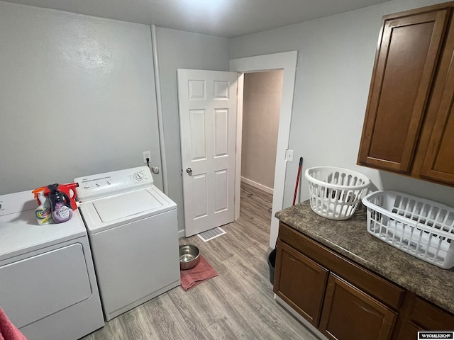 laundry area featuring cabinets, separate washer and dryer, and light hardwood / wood-style flooring