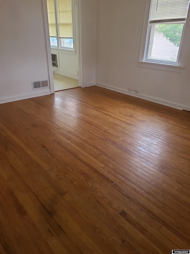 spare room featuring plenty of natural light, light hardwood / wood-style floors, and a wall mounted AC