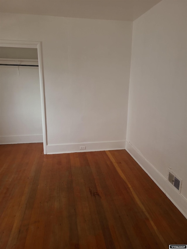 unfurnished bedroom with dark hardwood / wood-style flooring and a closet