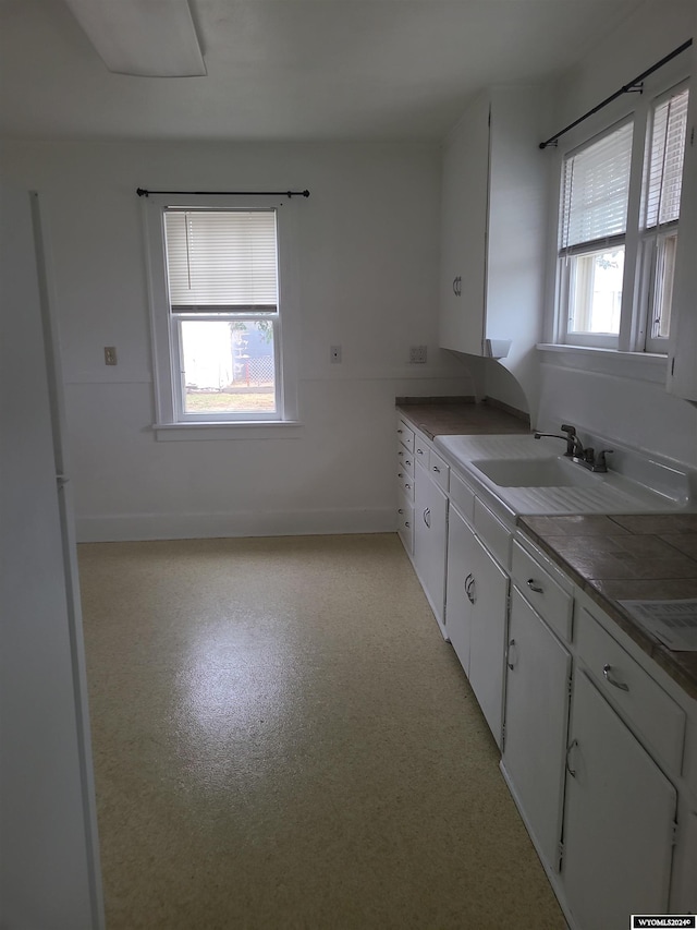 kitchen featuring sink, white cabinets, a healthy amount of sunlight, and white refrigerator