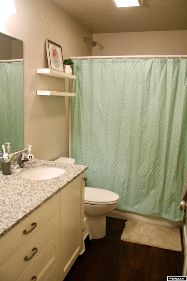 bathroom featuring a shower with curtain, vanity, a textured ceiling, hardwood / wood-style flooring, and toilet