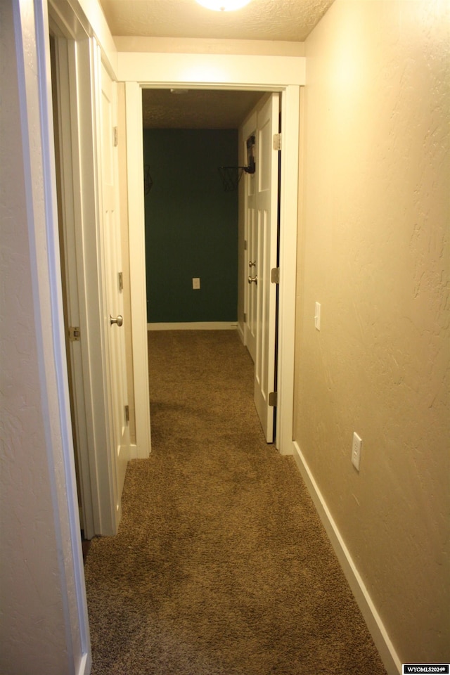 corridor featuring dark carpet and a textured ceiling