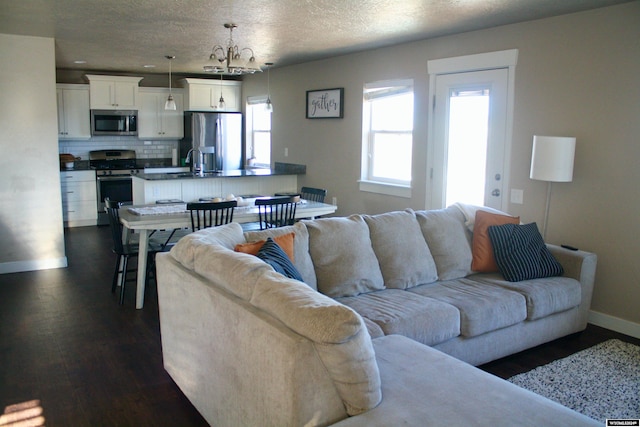 living room with a textured ceiling, sink, dark wood-type flooring, and a chandelier