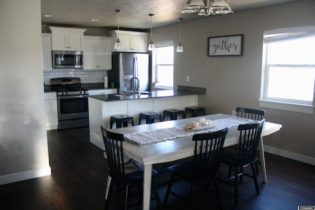 dining room featuring a textured ceiling, sink, and dark wood-type flooring