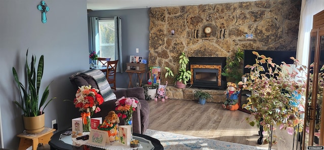 living room featuring a stone fireplace and wood-type flooring