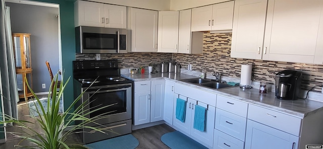 kitchen with white cabinets, decorative backsplash, stainless steel appliances, and sink