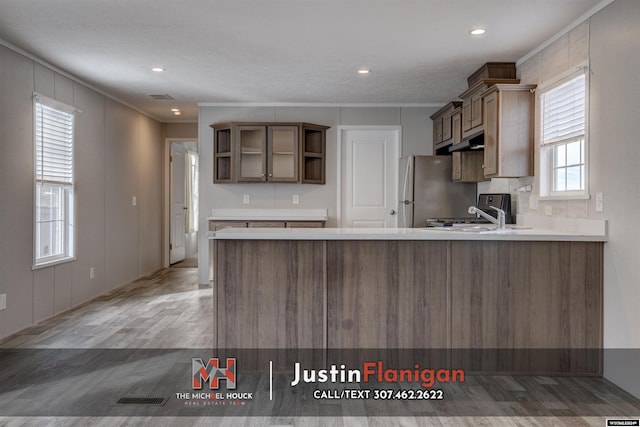 kitchen featuring hardwood / wood-style flooring, stainless steel refrigerator, kitchen peninsula, and a wealth of natural light