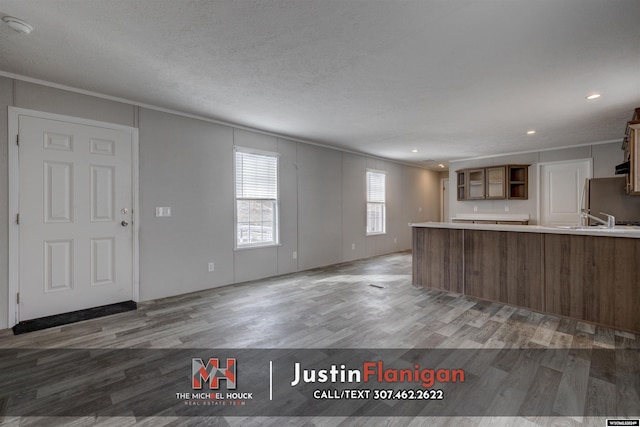 kitchen featuring stainless steel fridge, crown molding, wood-type flooring, and a textured ceiling