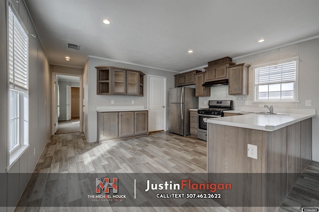 kitchen featuring kitchen peninsula, sink, light hardwood / wood-style flooring, and appliances with stainless steel finishes