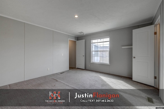 carpeted empty room featuring a textured ceiling