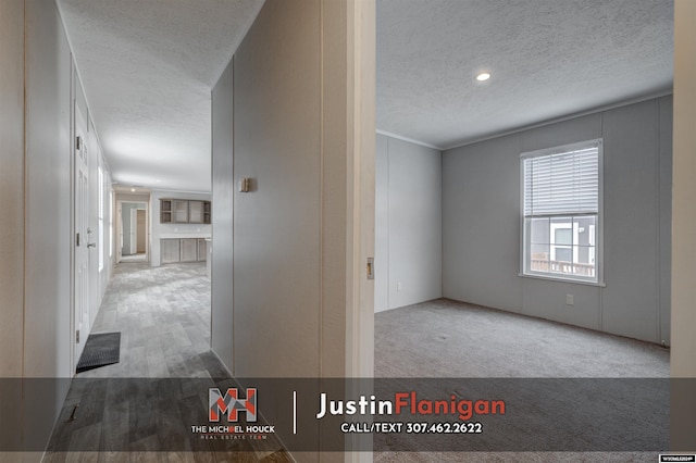 hallway with light wood-type flooring and a textured ceiling