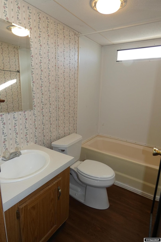 bathroom with hardwood / wood-style floors, vanity, toilet, and a tub to relax in